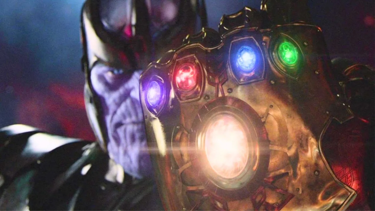 Replica dourada da Infinity Gauntlet com pedras preciosas reais sobre fundo de veludo, ao lado do logotipo da Marvel