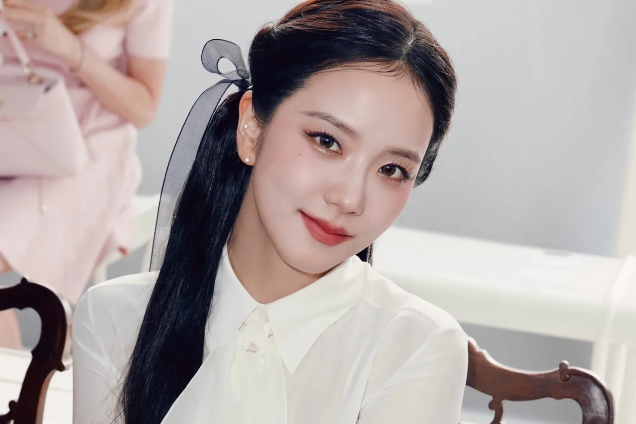 Jisoo segura seu light stick em forma de sorvete, com cores pastel e o logo do BLACKPINK ao fundo