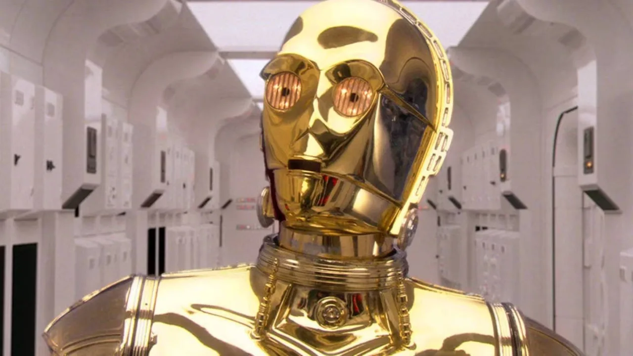 Luva esquerda de C‑3PO, em metal dourado, repousa sobre fundo escuro com o logo da Heritage Auctions ao lado