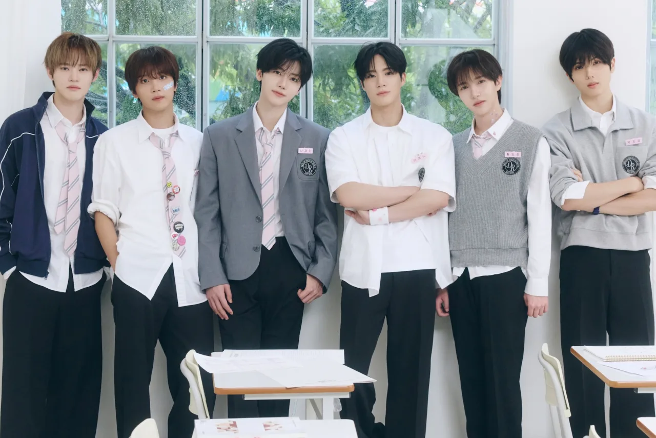 Membros do NCT DREAM posam em conjunto, vestindo roupas futuristas, com o título ‘DREAM AFTER DREAM’ e a data 9/11