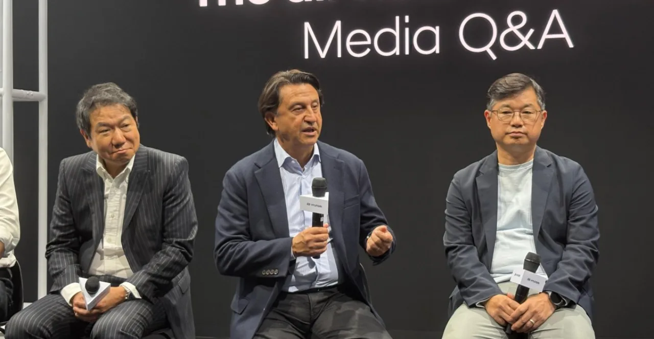 CEO da Hyundai em pé ao lado de carros elétricos chineses, com logotipo da Hyundai e símbolo de campo nivelado ao fundo