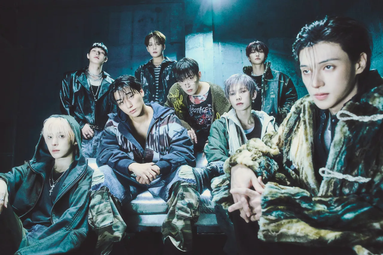 Membros do ATEEZ posam ao lado da capa colorida de “GOLDEN HOUR : Part.6” com a lista de faixas exibida