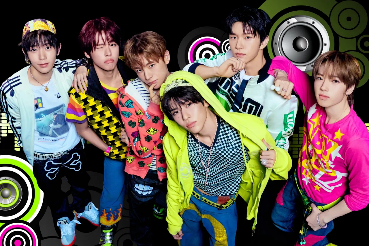 Membros de NCT WISH posam sorrindo segurando o mini‑álbum I SPY, com o logotipo da banda ao fundo