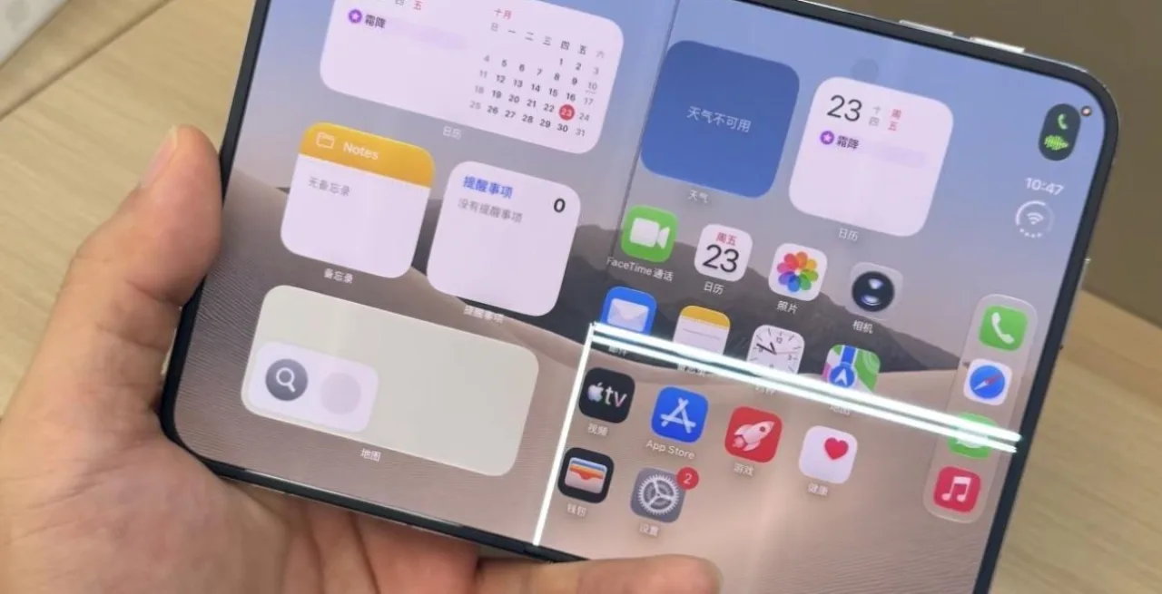 iPhone Duo aberto com dobradiça quebrada e tela rachada ao centro, mostrando fissura em forma de X