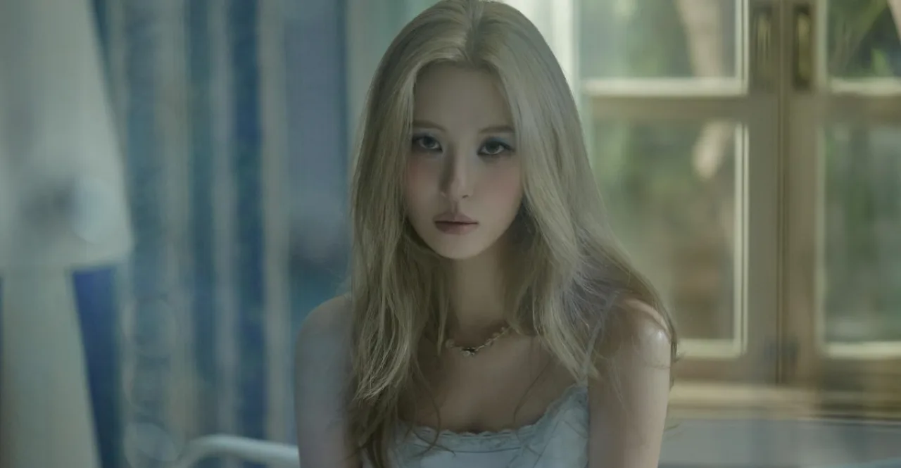 Sunmi aparece sorrindo ao lado de um tablet exibindo o logo do Notion, com um cotonete de limpeza de ouvido ao alcance
